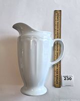 Side view of the large white porcelain pitcher with ruler showing height.