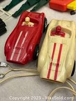 Close-up image showing red and cream slot cars with drivers and racing stripes.