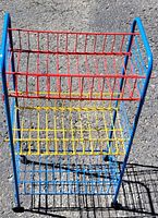 Top-down view of the multi-colored wire storage rack showing three shelves: red, yellow, and blue coated metal wire baskets, with blue coated metal tubing frame.