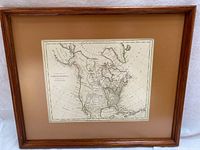 Framed antique map showing the entire framed piece including the wooden frame and brown mat.