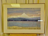 Framed hand sewed art panel featuring a mountain scene with multiple fabric layers and hand stitched grass in the foreground.