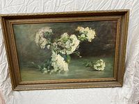 Full view of the oil painting with floral still life in a decorative gold frame.
