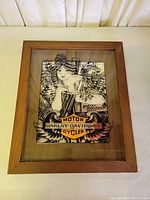 Framed glass mirror showing the Harley Davidson artwork including a woman and the Harley Davidson Motor Cycles logo seen from front.