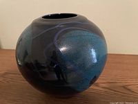 Photo of glossy blue pottery bowl showing rounded shape, wide opening, and blue/black color variations