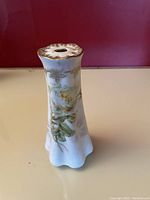 Porcelain vase with fluted shape, gold decoration, and floral design on light background.