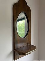 Side view of vintage pine wood wall mirror with oval glass and small shelf below