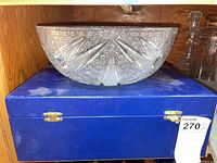 Side view of the crystal bowl resting on a blue box, showing the textured cut glass pattern on the exterior.