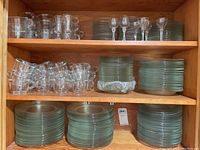 Glass stemware with long stems on top shelf with a stack of plates