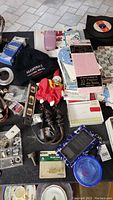 Photo of lot showing various hardware parts, 45 RPM records, cards, doll, and phone.