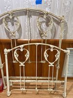 Front view of assembled iron bed frame showing headboard and footboard with ornate ironwork design