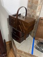 Closed wooden multi-tier sewing box with handle, showing its compact design and dark wood finish.