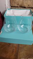 Two clear glasses placed in Tiffany & Co. signature blue box with white tissue paper.
