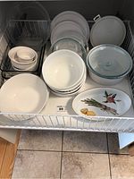Top-down view of bake ware assortment including ceramic and glass casserole dishes, bowls, ramekins, along with lids and plates.