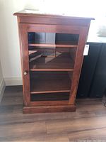 Full view of wooden display cabinet showing front glass door and base molding.