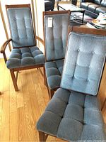 Front view of three chairs showing tufted blue seats and backs on wood frames