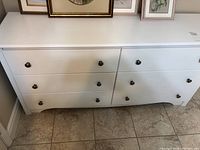 Front view of white dresser showing all six drawers and brushed nickel handles.