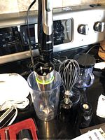 Braun MultiQuick 9 hand blender with whisk, chopping container, beaker, and attachments on a kitchen counter near stove.