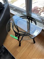 Top view of round glass end table showing clear glass surface and black metal frame