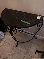 Front angle view of the half-moon table showing faux marble top and metal scrollwork frame.