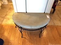 Front view of light beige cushioned bench with black metal frame on wood floor.