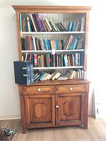 Full view of vintage wooden hutch with various books on attached shelves.