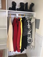Winter coats and leather boots hung on hangers in a closet, showing all coats and boots in the lot.