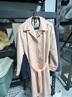Peach London Fog trench coat hanging on a rack with visible collar and buttons