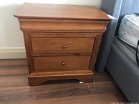 Front view of the wooden nightstand showing two drawers and overall design