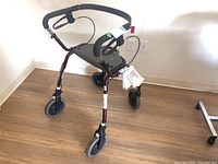 Front view showing hand grips with hand brakes, padded seat, and overall walker structure.