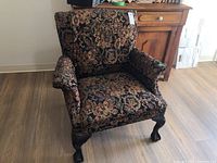 Front full view of wingback chair showing the floral tapestry fabric and overall design.