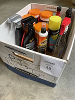 Photo of nine various car cleaning products including sprays, aerosol cans, and liquids in a cardboard box.