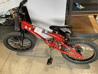 Side and top view of the red children's bicycle showing frame, tires, pedals, and seat.