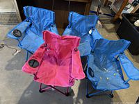 Top-down view of four children's camping chairs showing blue and pink colors with cup holders on armrests.