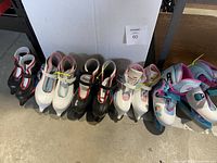 Seven pairs of children's ice skates in various colors and sizes neatly lined up
