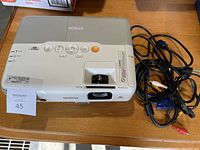 Top view of Epson PowerLite 905 projector showing buttons, lens, and branding with attached cables.