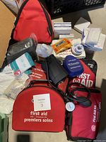 Lot contents including red first aid kits, medical supplies, and equipment spread out on floor.