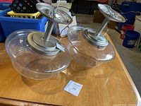 Two ceiling light fixtures with metal bases and clear bubbled glass shades placed on wood tabletop.
