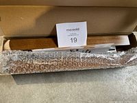 Photo of the unassembled wooden piece and metal frame wrapped in bubble wrap inside the cardboard box.