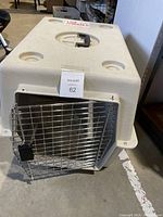 Front view of the plastic pet carrier with metal wire door closed, showing ventilation holes on top and locking latch.