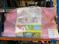 Photo of play tent in packaging showing pink fabric and label.