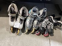 Three pairs of roller skates side by side on floor, two inline and one traditional skate