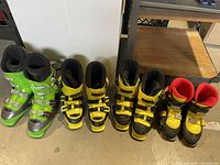 Photo showing 5 ski boots of varying colors: two green, two yellow with black, and one yellow with black/red interior.