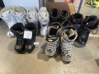 Photo of seven pairs of snowboard boots arranged in two rows showing variety of styles and colors.