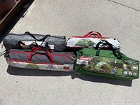 Four tents packed in bags on pavement, various colors and brands visible.