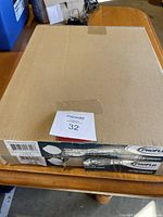 Two unopened cardboard boxes each containing a round front white toilet seat by ProFlo, model PFTSE1000WH. Boxes are stacked on a wooden surface showing the product labels and barcodes.