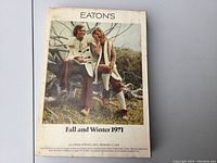 Front cover of the Eaton's 1971 Fall and Winter catalogue showing two models in period fall clothing seated on tree branches.