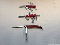 Three multi-tool cutters lying flat with tools extended, showing sizes and handle colors.