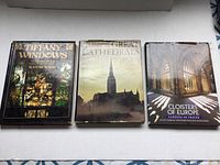 Photo of three hardcover books: 'Tiffany Windows', 'The Great Cathedrals', and 'Cloisters of Europe' laid flat showing covers and dust jackets.