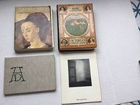 Four art books laid out on a white surface showing covers and sizes.