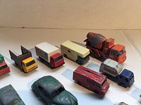 Various toy vehicles arranged in rows showing condition, color, and types, including cement mixer and box trucks